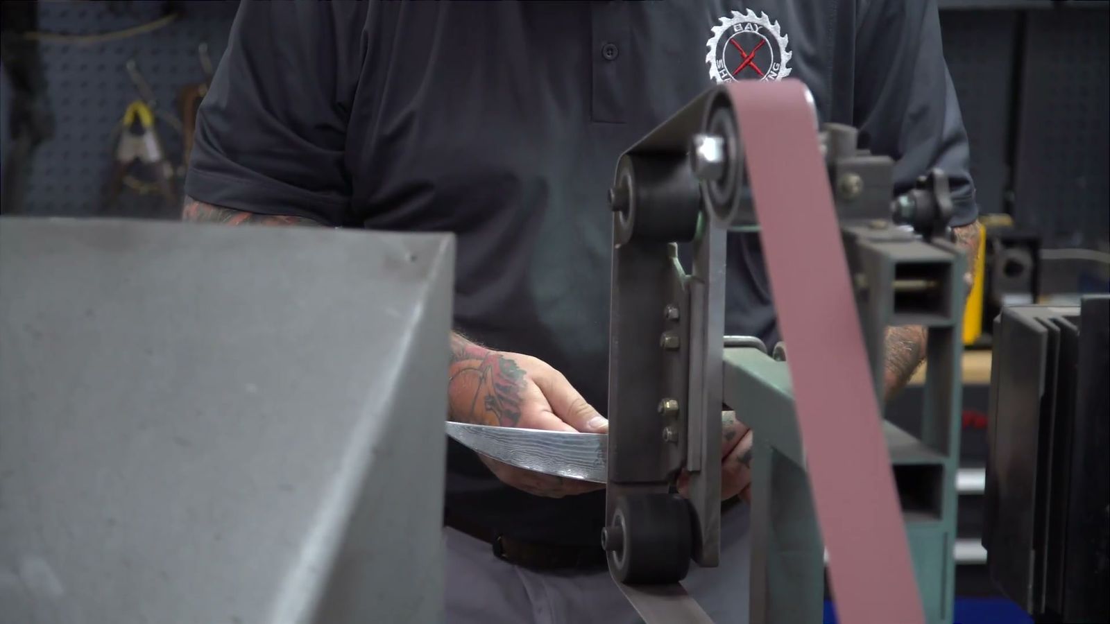 Sharpening a blade at the belt grinder in the Bay Sharpening shop