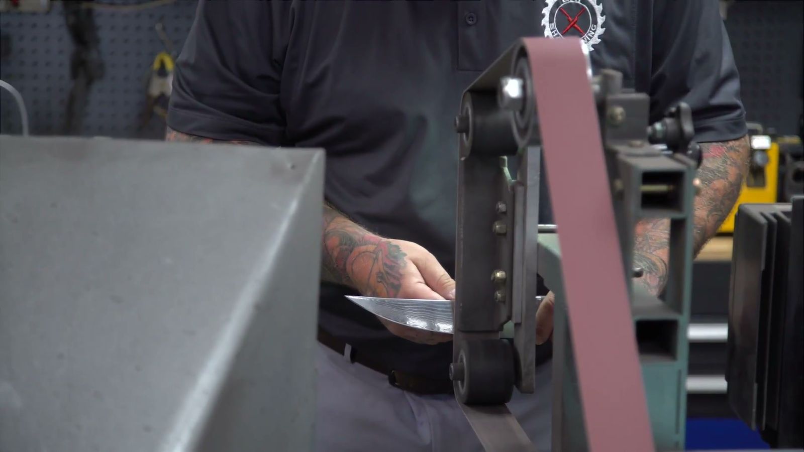 Sharpening a blade on the belt grinder at the Bay Sharpening shop